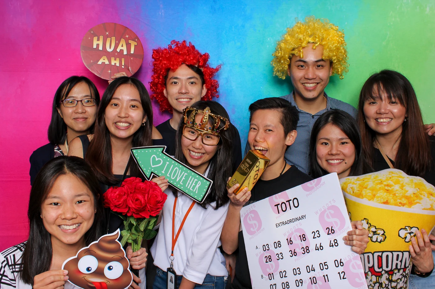 Guests with colourful photo booth props in front of Whoots’ rainbow Spectrum backdrop